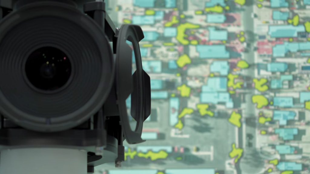 Aerial survey camera in front of a classified aerial image showing buildings and vegetation